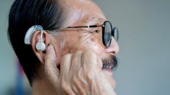 Ear: senior man adjusting hearing aid 1839577345
