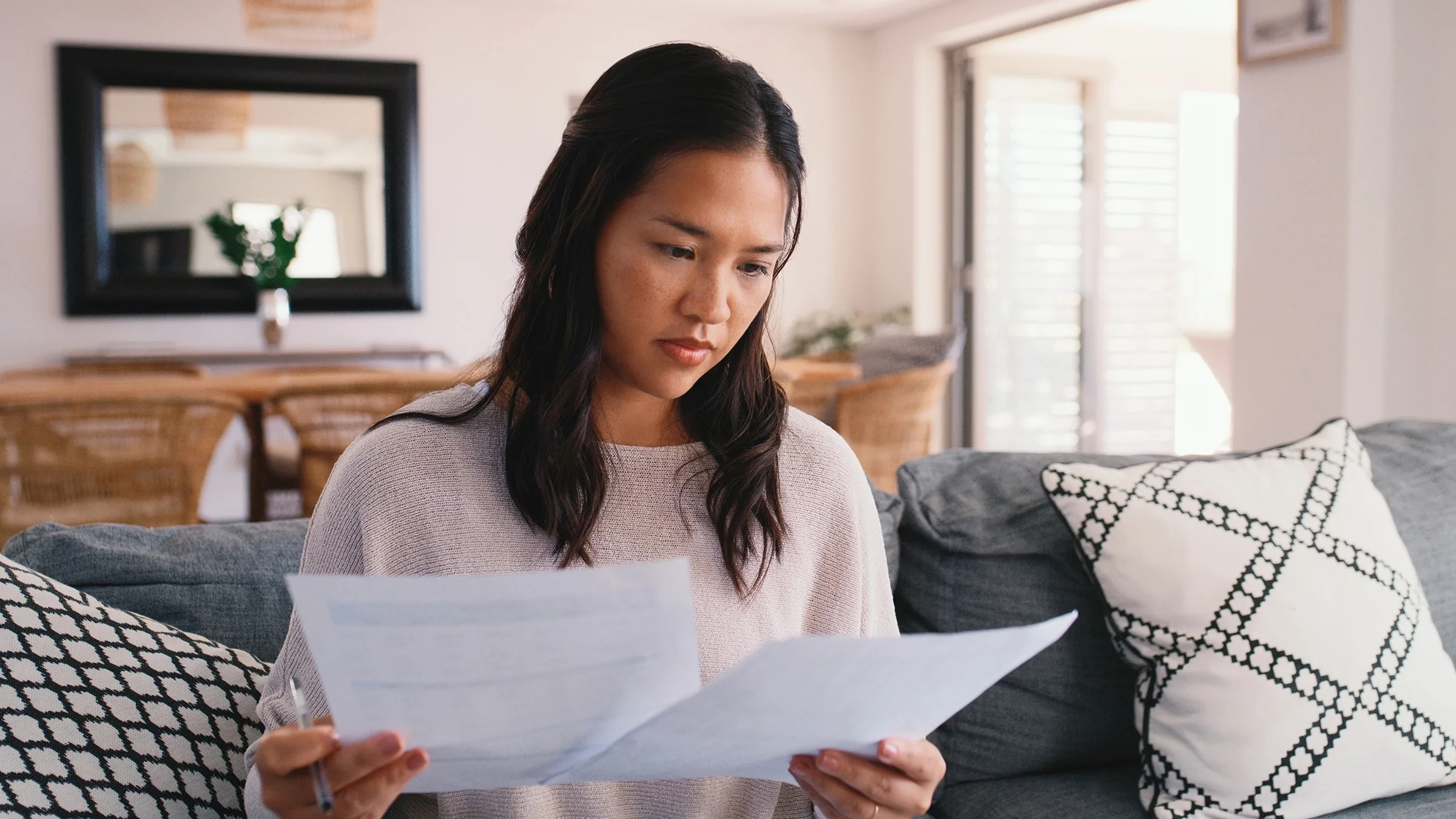 A woman reviews paperwork at home.