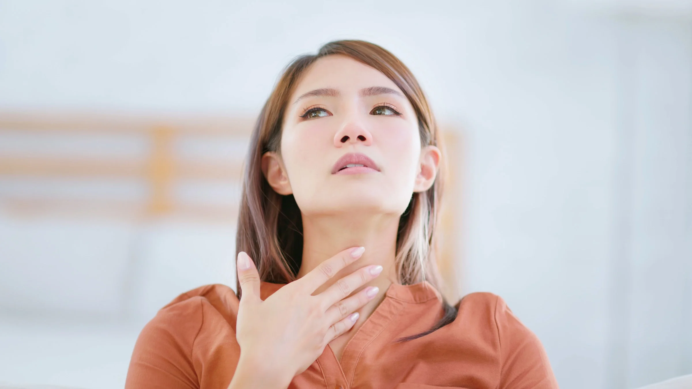 A person touching their throat.