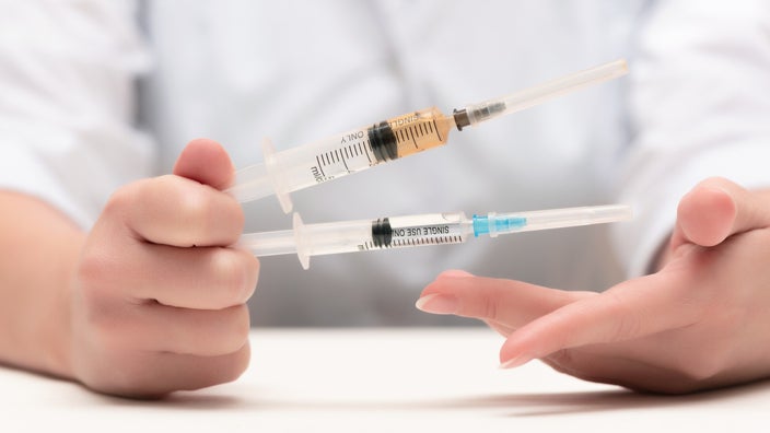 Cropped image of a doctor holding two syringes.