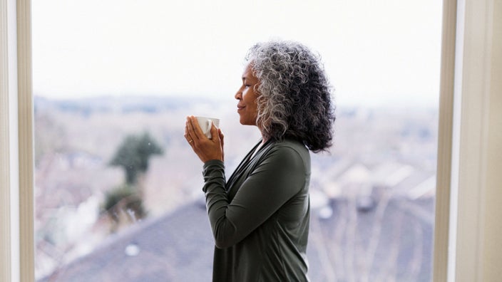 A woman pauses to take a deep breath at home.