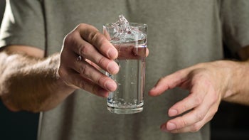 Medication education: Hand tremors: shaky hands holding glass of water splash-1390058228