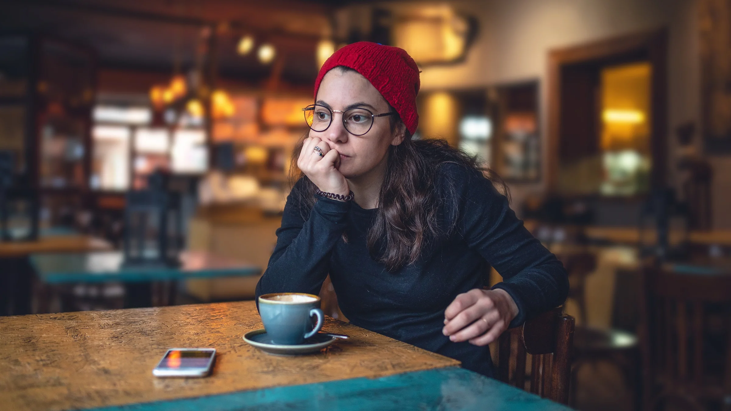 Sad woman in a red beanie in a coffee shop.