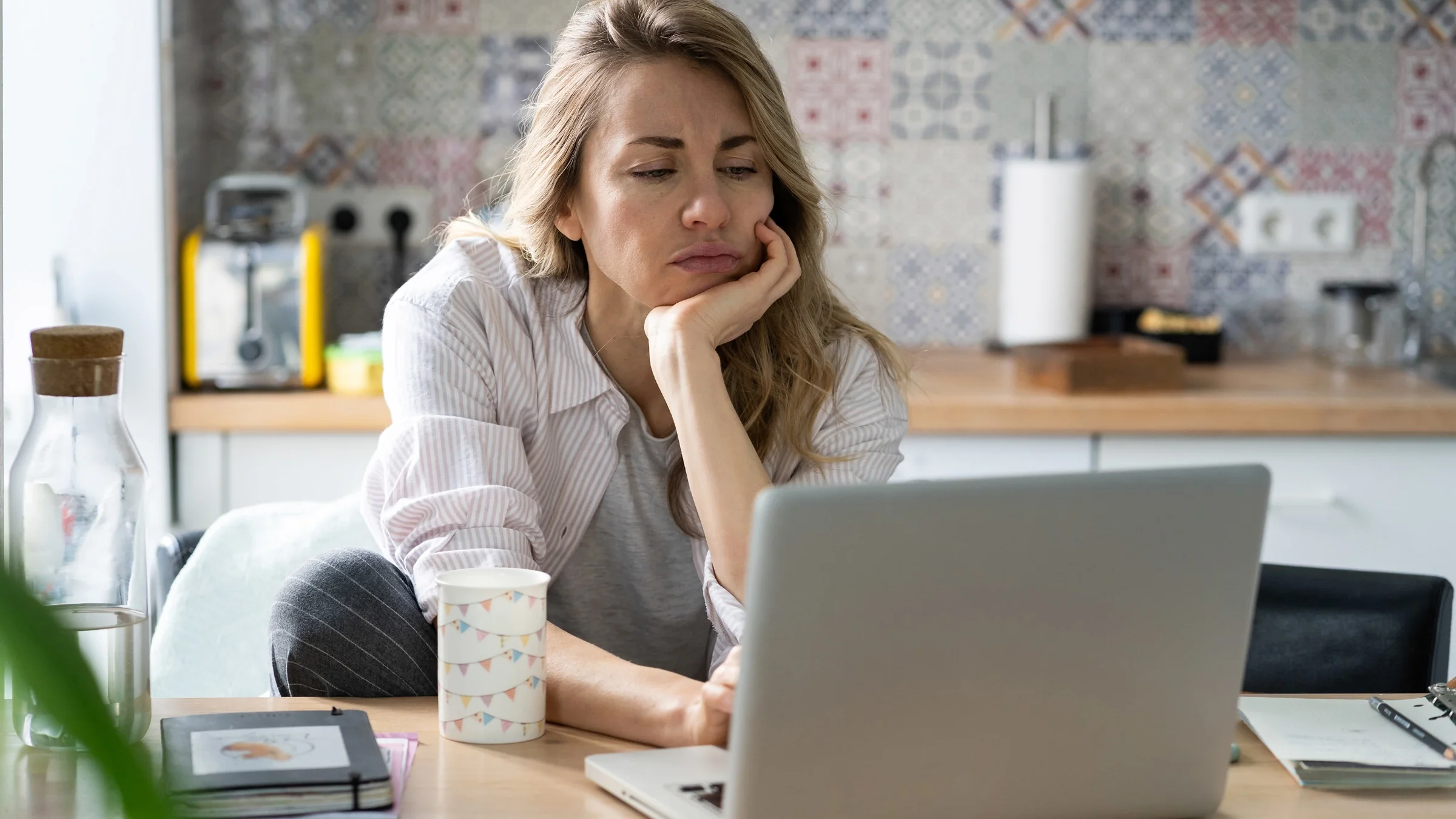 A stressed out person looking at their laptop.