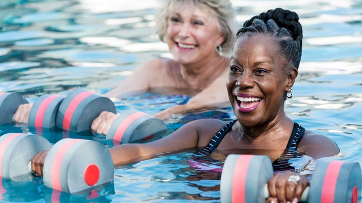Two women doing water aerobics with weights.