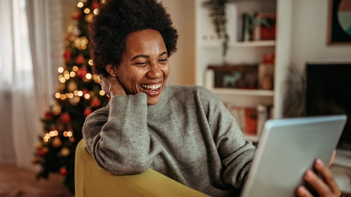 Young woman video calling on her tablet with Christmas tree in the background