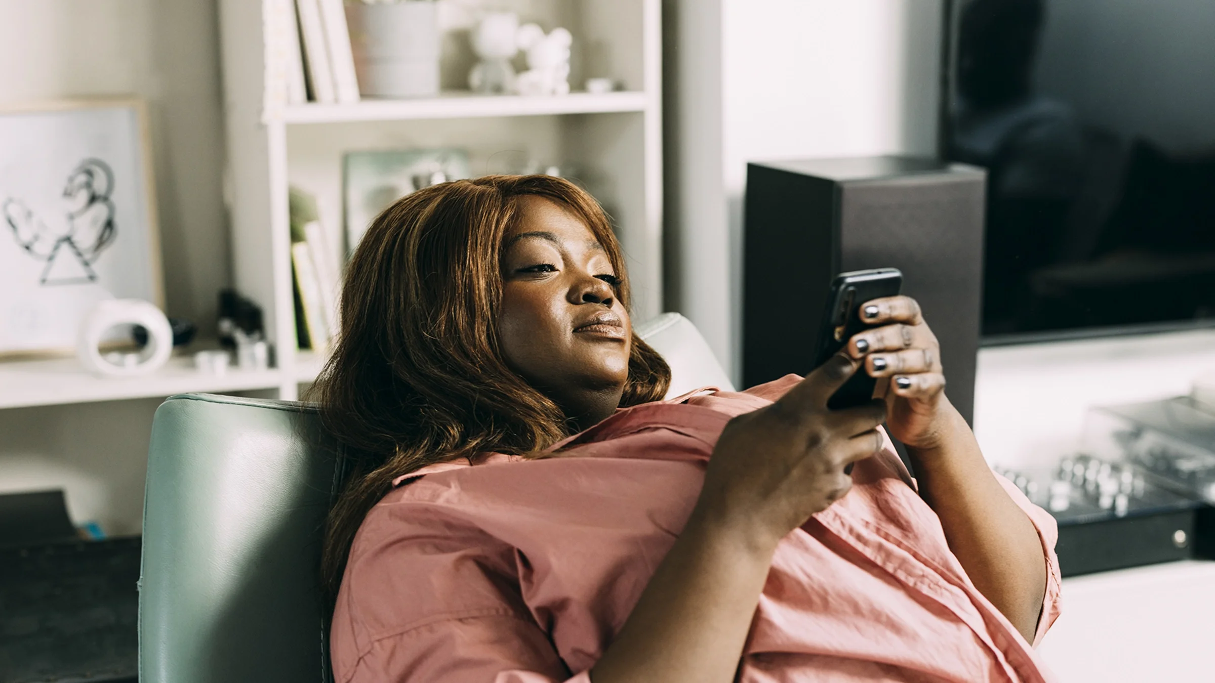 A woman is looking at her phone while relaxing at home.