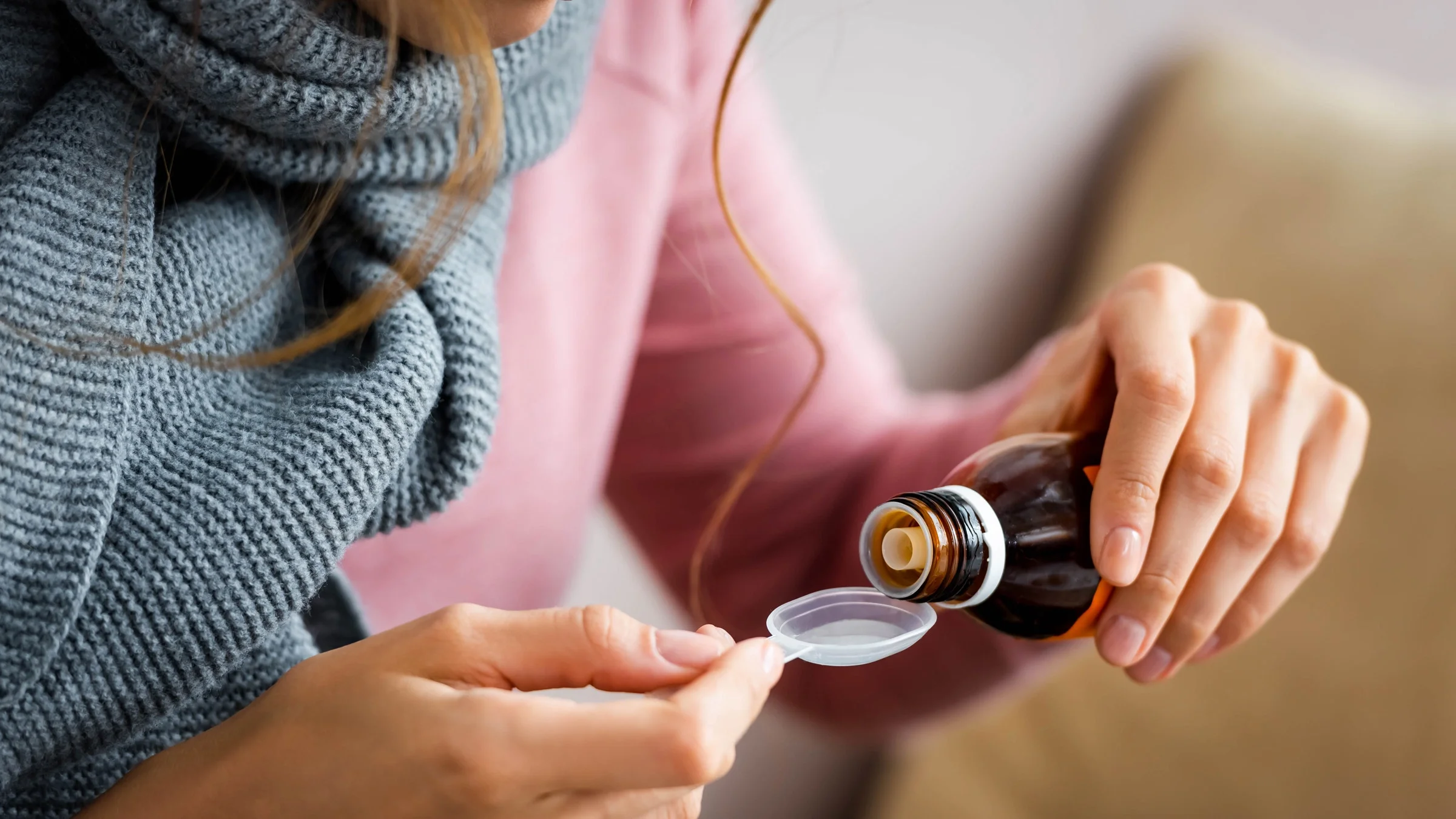 Close-up of someone pouring cough syrup.