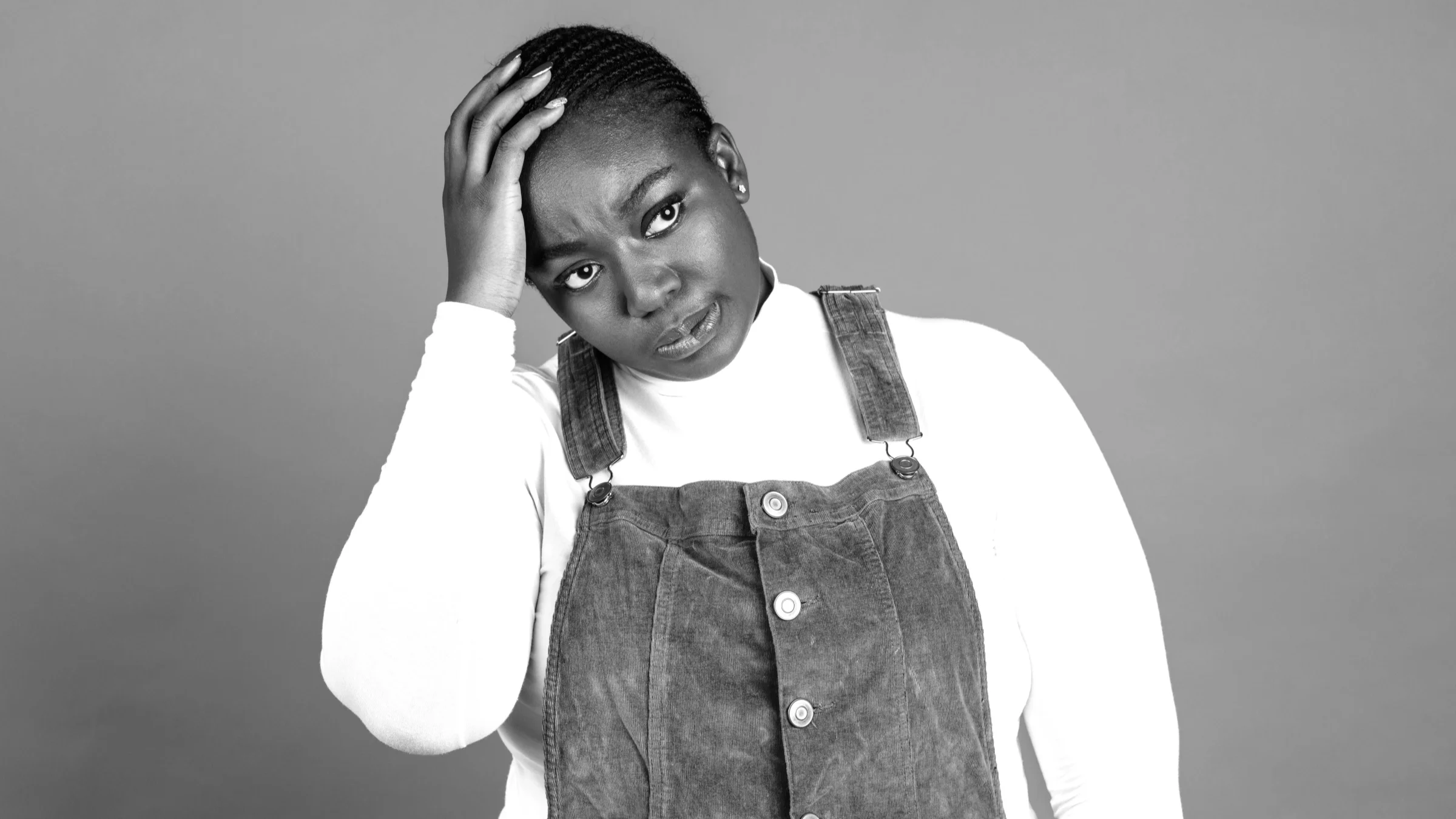 Black and white portrait of a Black woman with her hand on her head in frustration.