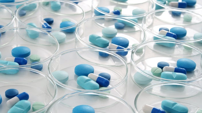 A variety of blue pills in petri dishes.