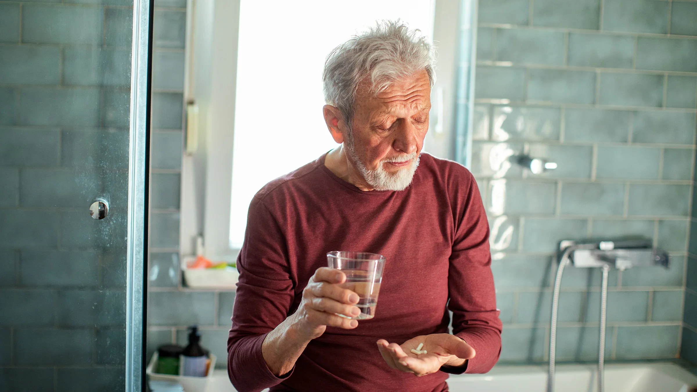 A man takes medicine with a glass of water.
vorDa/E+k via Getty Images