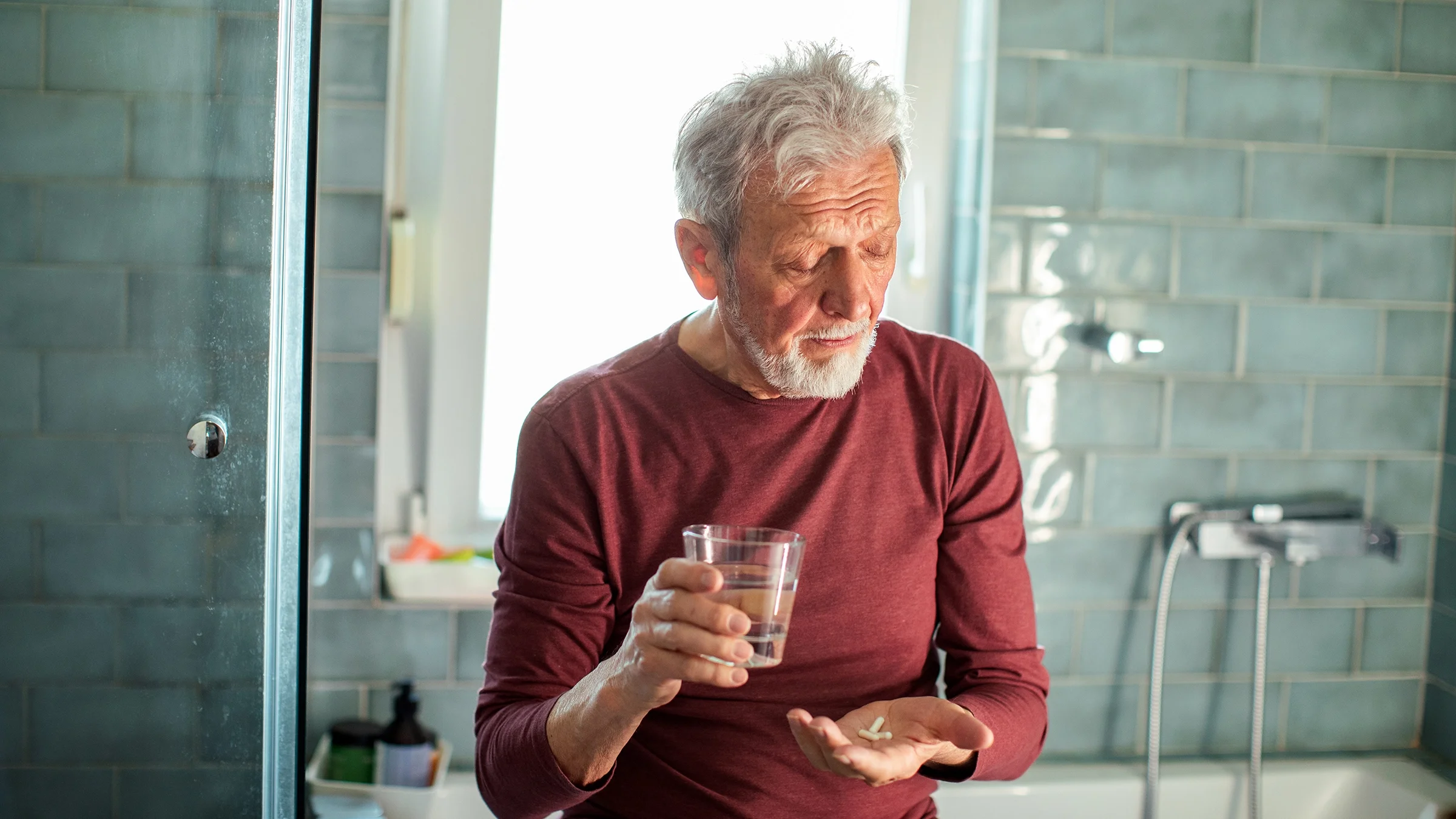 A man takes medicine with a glass of water.
