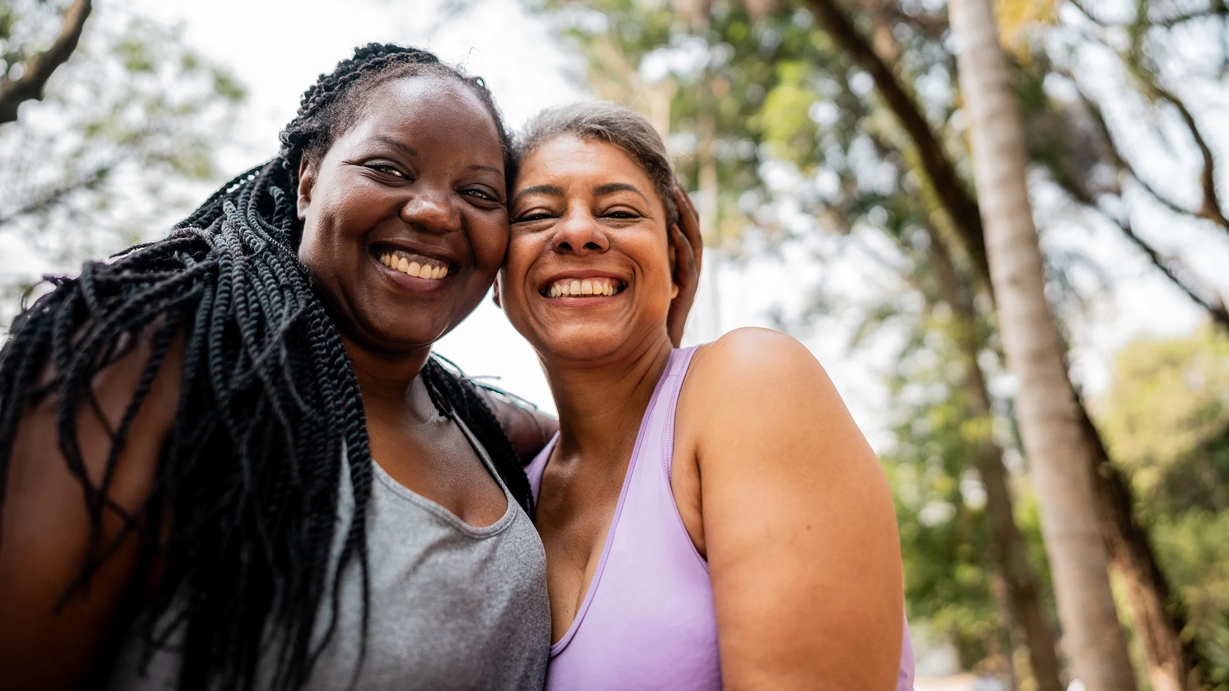 This portrait depicts two women smiling outdoors.