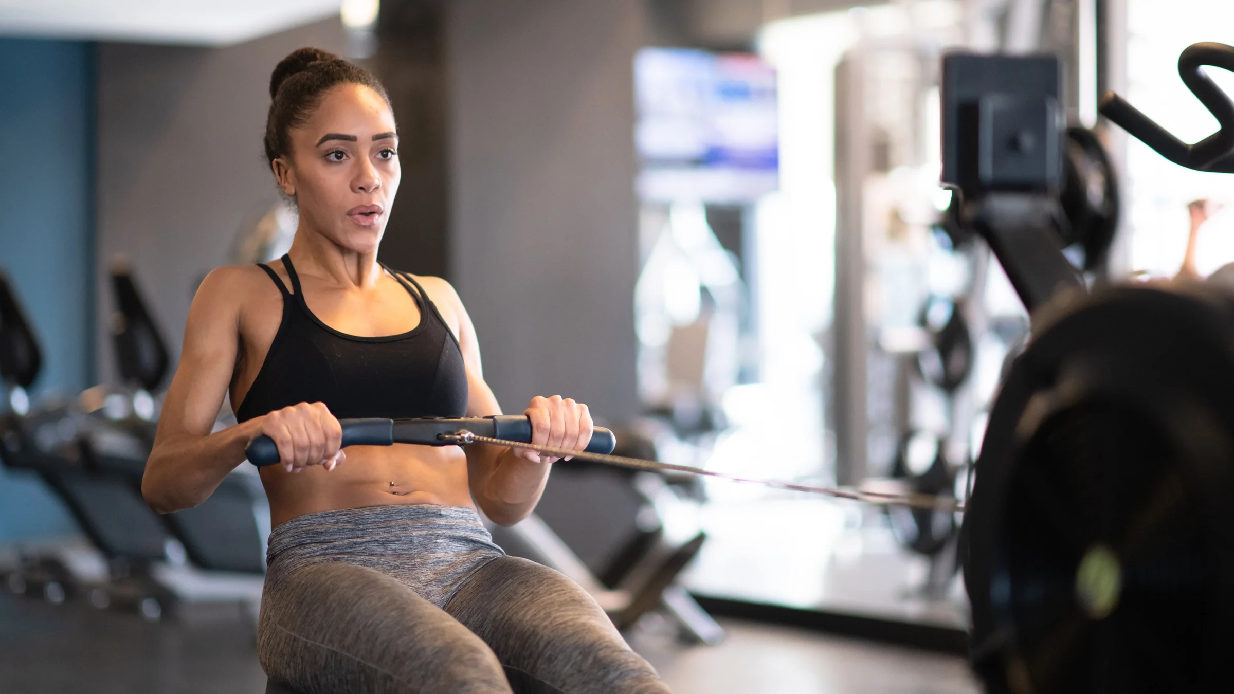 A woman uses a rowing machine at the gym.