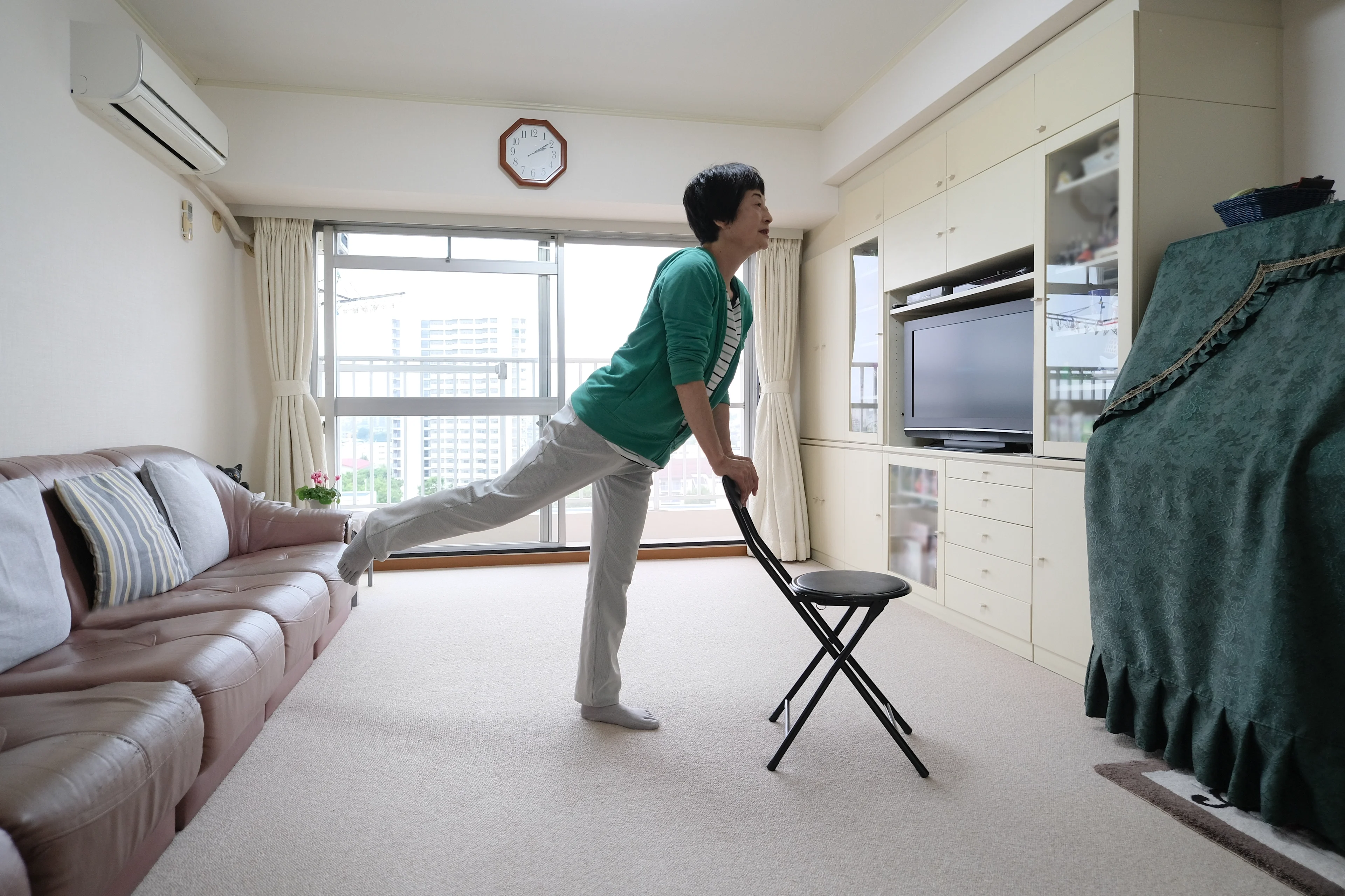 A woman exercising at home with a chair.