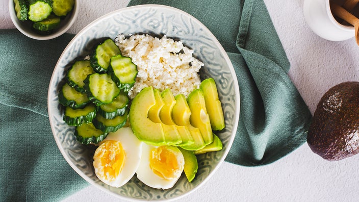 Bowl of cottage cheese with boiled eggs, cucumber, and avocado