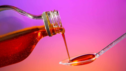 Cough medicine is poured onto a spoon in front of colorful background.
Daniel Heighton/iStock via Getty Images Plus
