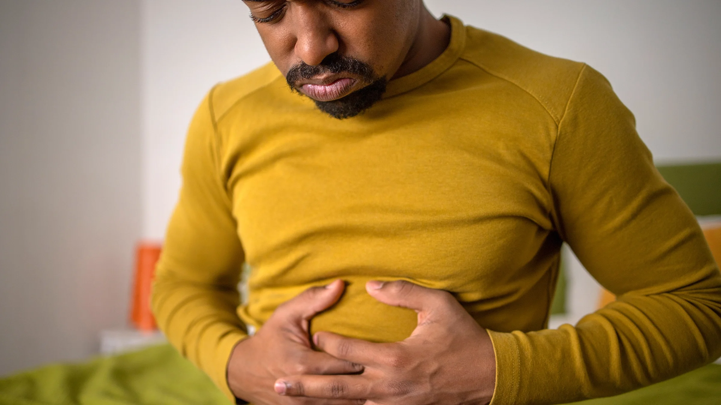 A man clutches his stomach in pain.