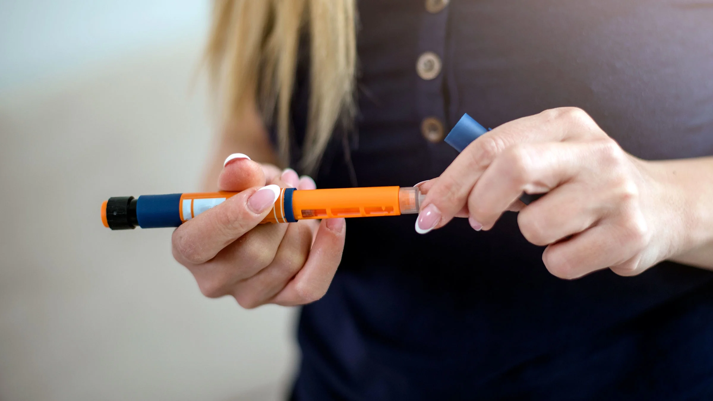 A close-up of a woman holding an insulin pen.