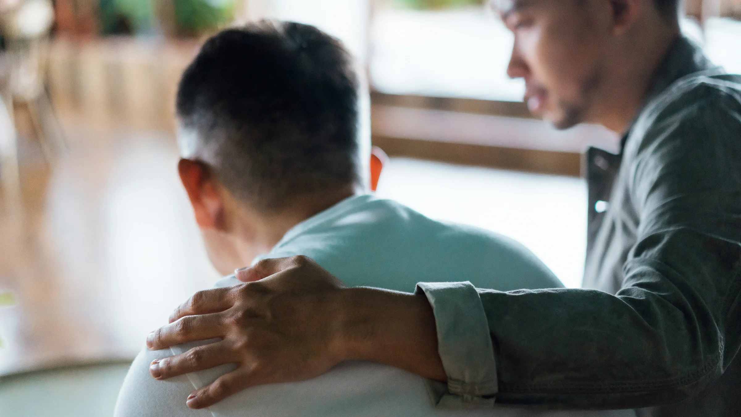 Family member supporting a young man with his arm around his shoulder.