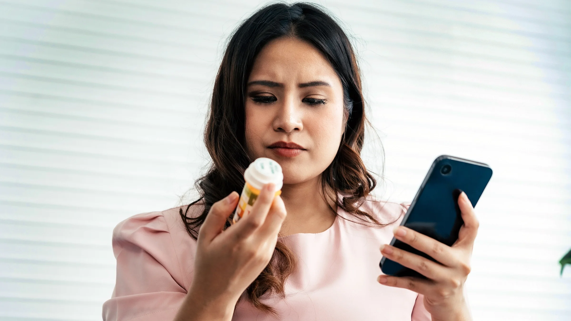 A woman reads the label of her prescription bottle.