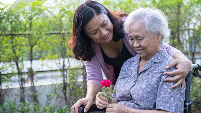 Senior health: delirium: elderly woman holding flower hugged by daughter 1417991109