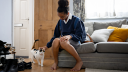 Teenage girl arriving home from school and greeting the cat.
andresr/E+ via Getty Images 