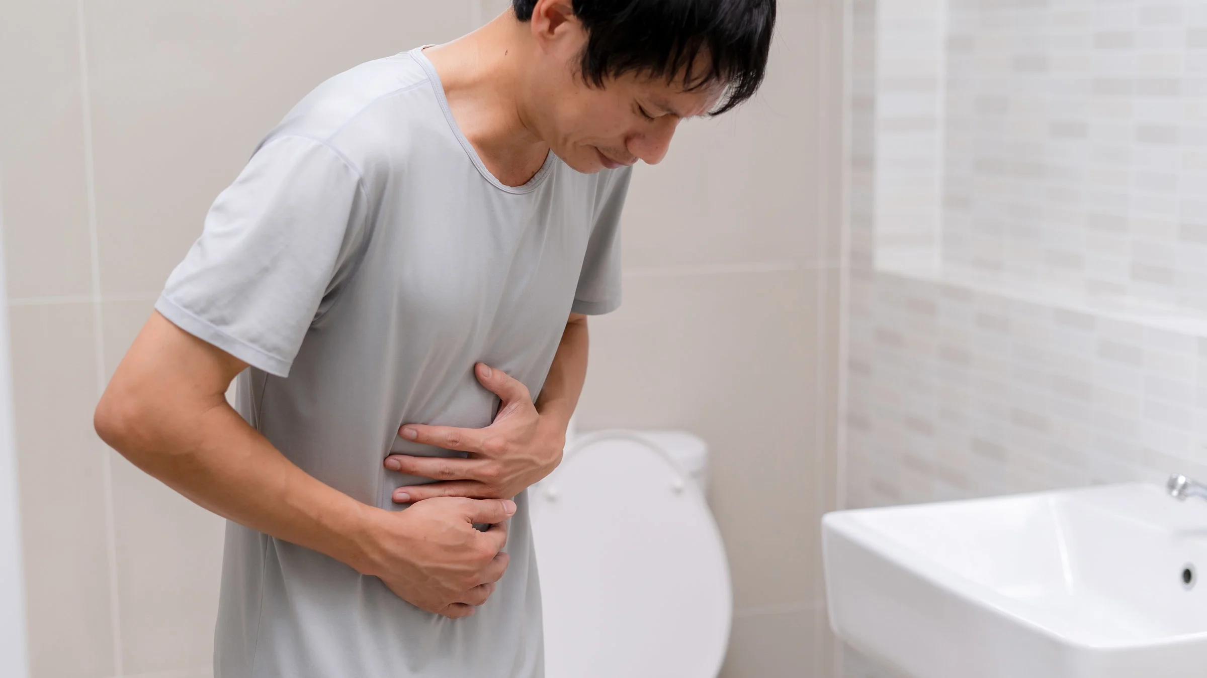 A man with stomach pain by the toilet.