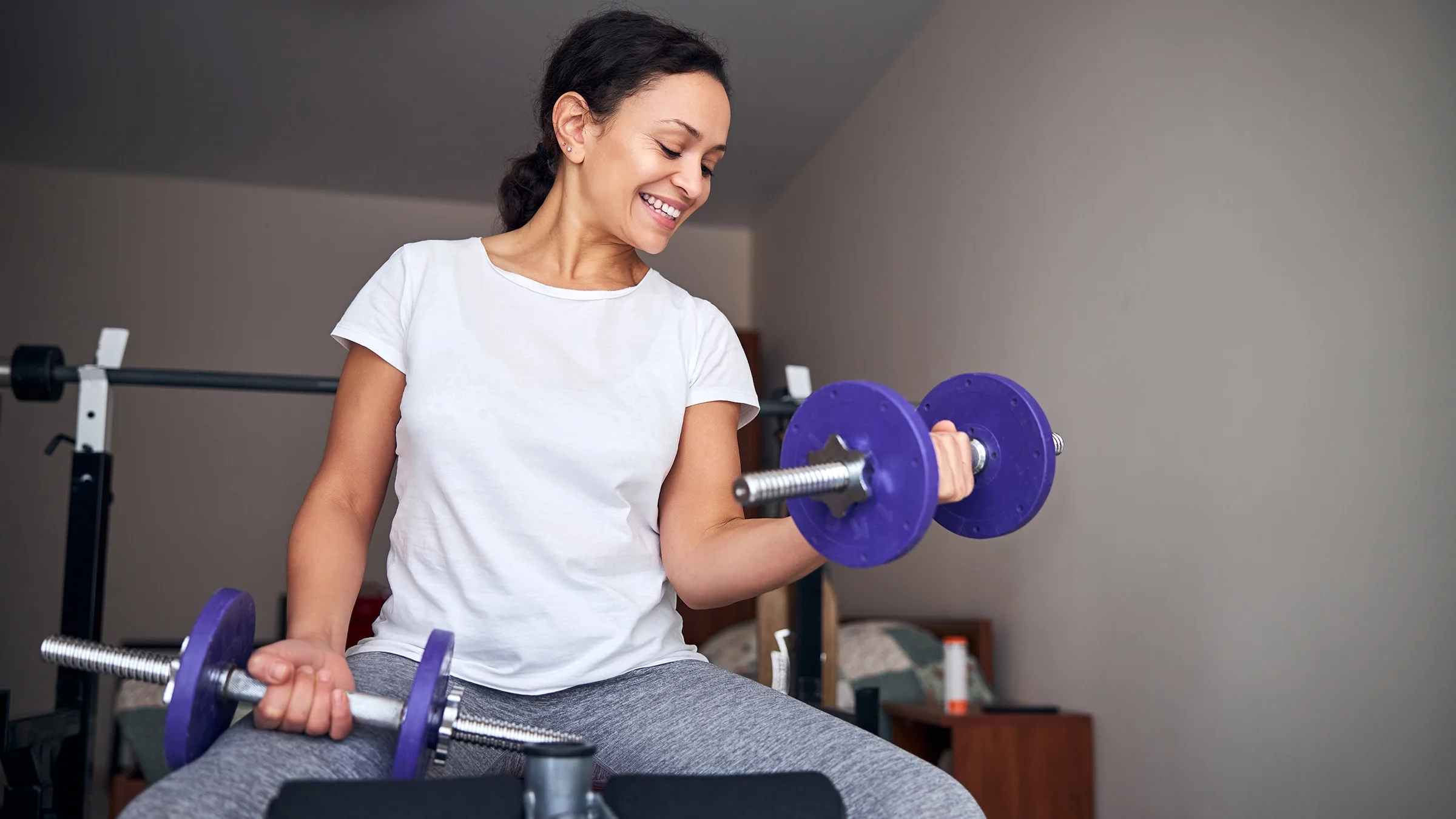 Woman doing seated bicep curls with barbells.