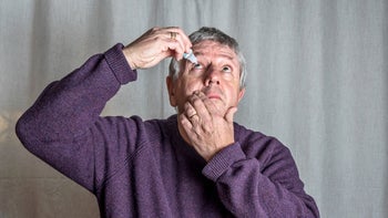 Eye: senior man inserting eye drops 1126894559
