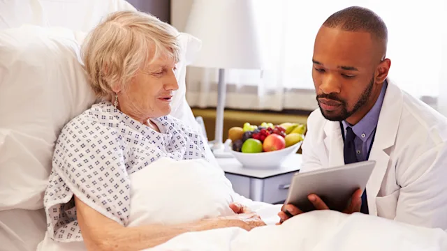 MedicareL Part A: doctor showing tablet to patient in hospital bed 488721380