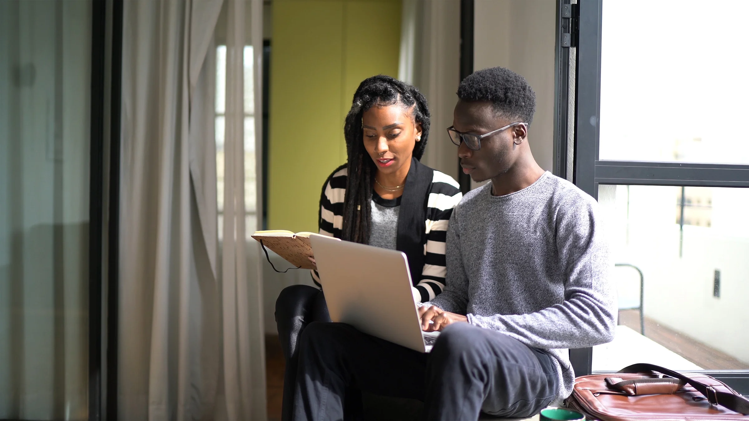 Couple sitting at home reviewing documents, notes, and finances online.