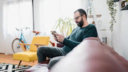 Man using his tablet while relaxing on the couch at home
DusanManic/E+ via Getty Images 