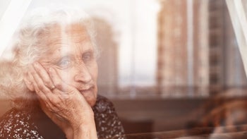 Mental health: Passive suicidal ideation: senior woman stares out window GettyImages-1221787895