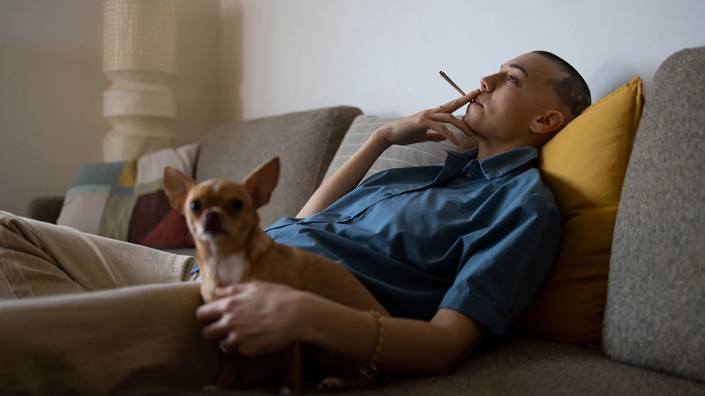 A relaxed person smokes marijuana at home.