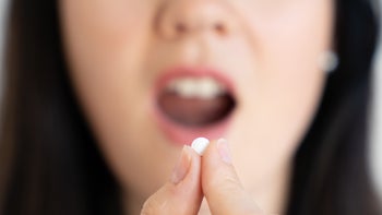 Health: Medication education: woman taking pill by mouth 1221036197