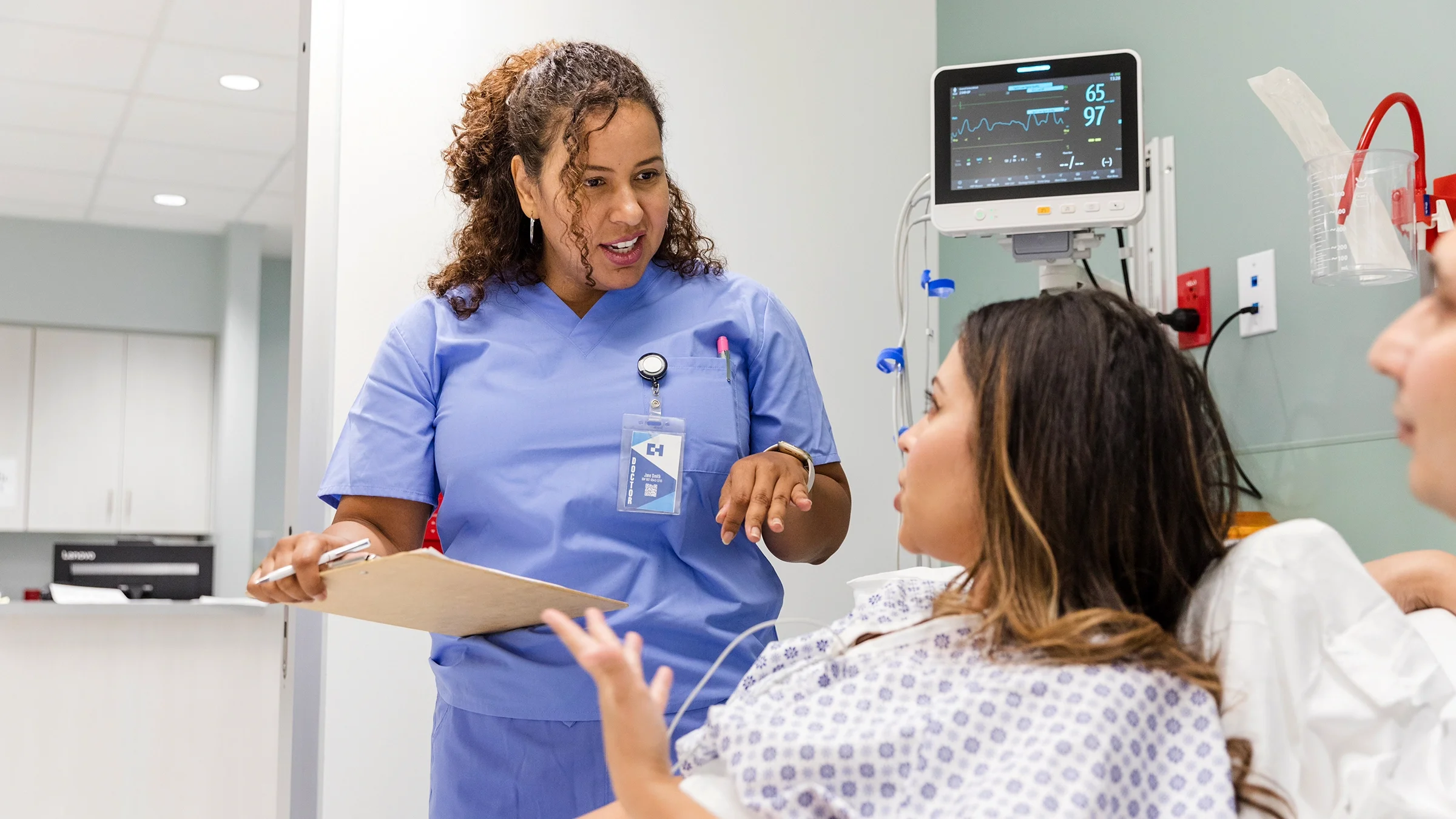 A nurse speaks with a woman in a hospital bed.