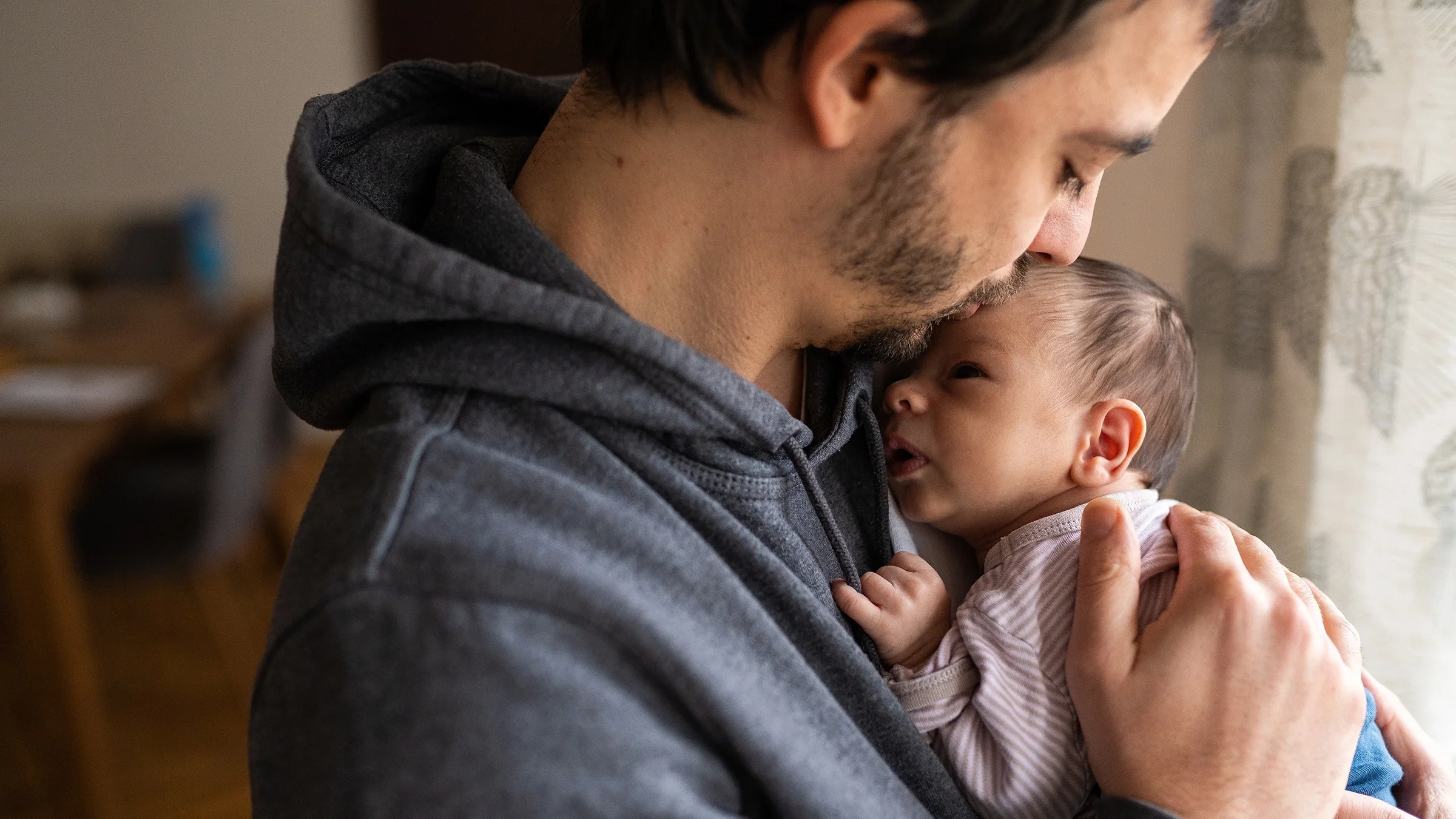 Portrait of a father holding his newborn to his chest.