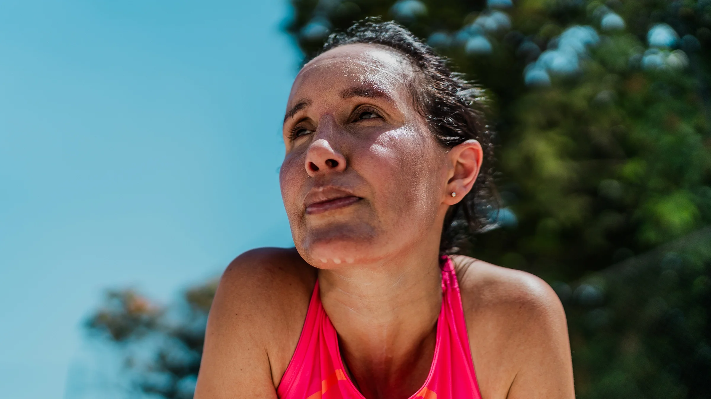 A woman sweats while doing sports outdoors.