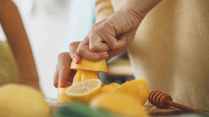Close-up woman squeezing lemon with honey.