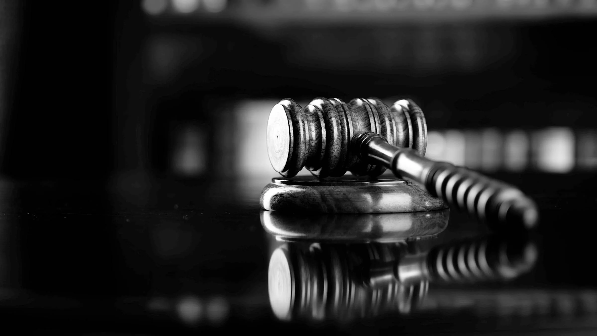 Black and white close-up of a gavel on a courtroom stand.
