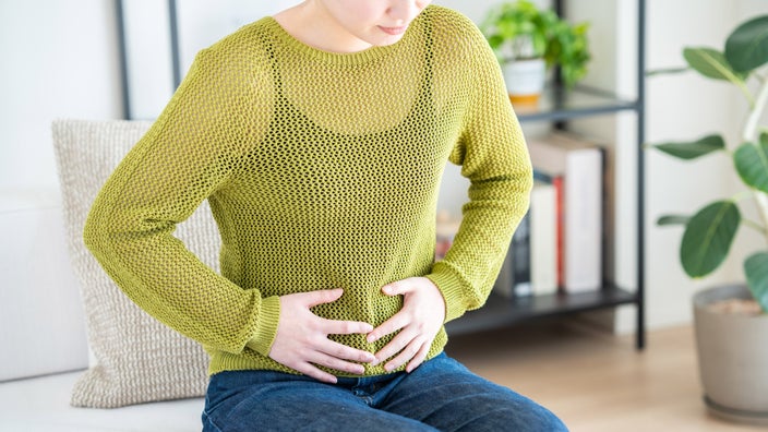 Close-up of a woman holding her stomach.