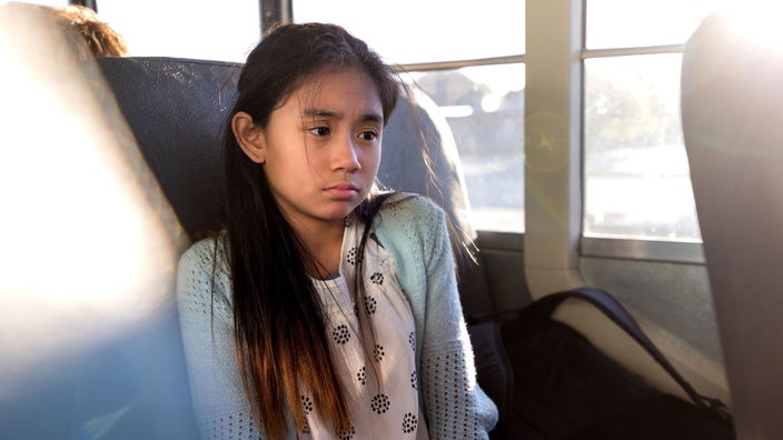 Sad child sitting on school bus.