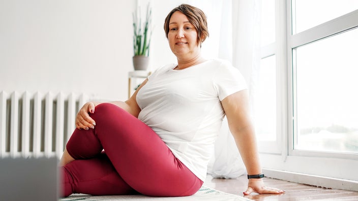 Woman practicing yoga at home via instruction on a laptop.
