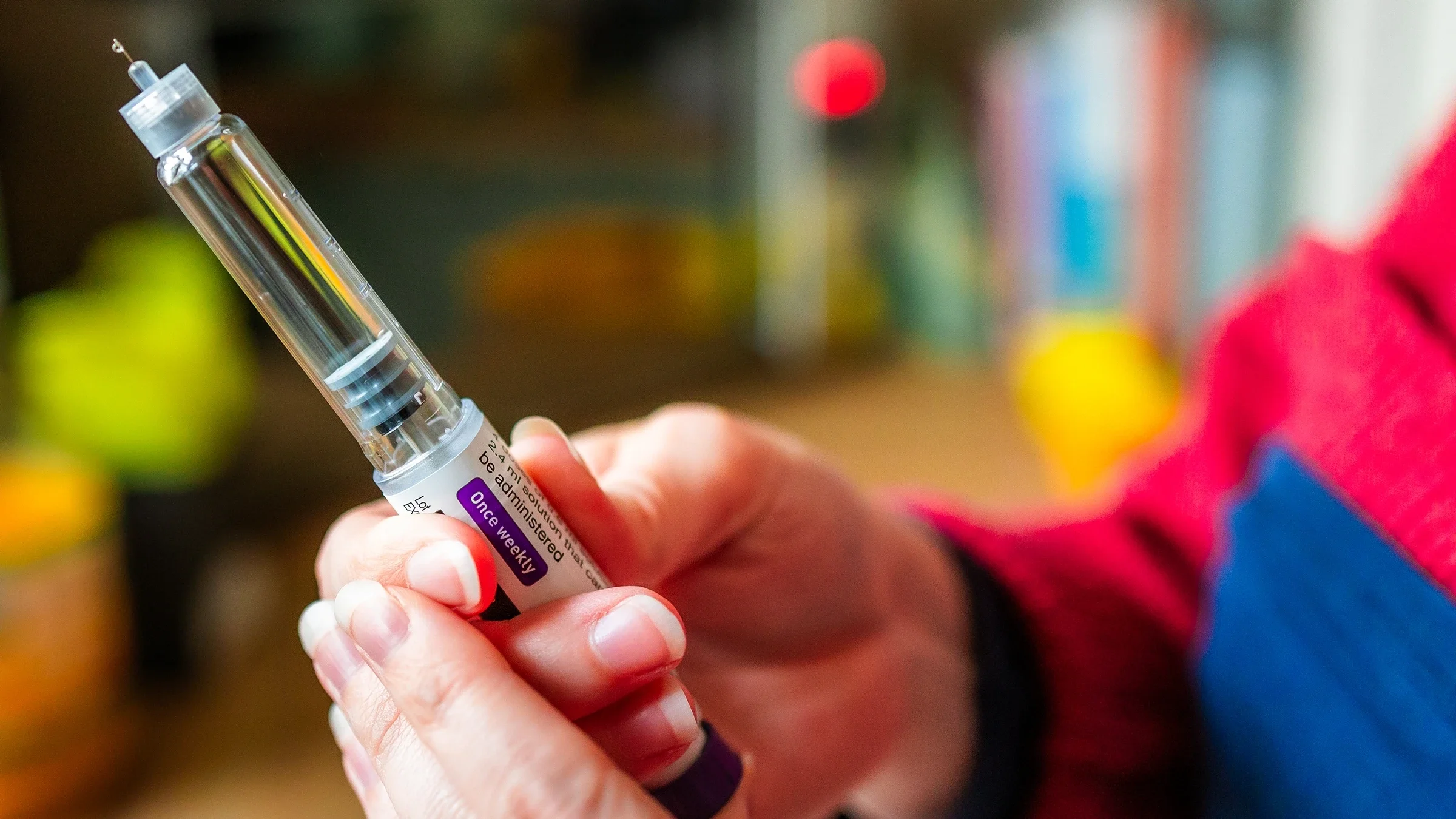 A person is preparing to administer a weight-loss injection in a close-up.