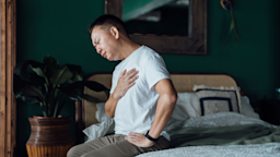 Man with eyes closed holding his chest in discomfort and has trouble breathing.
AsiaVision/E+ via Getty Images 
