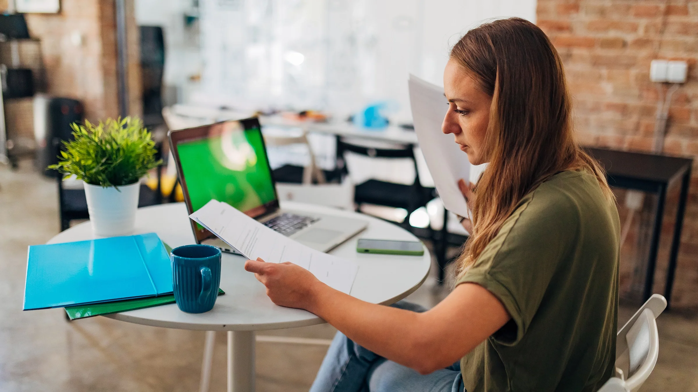 Woman arranges paperwork while sitting at a desk.