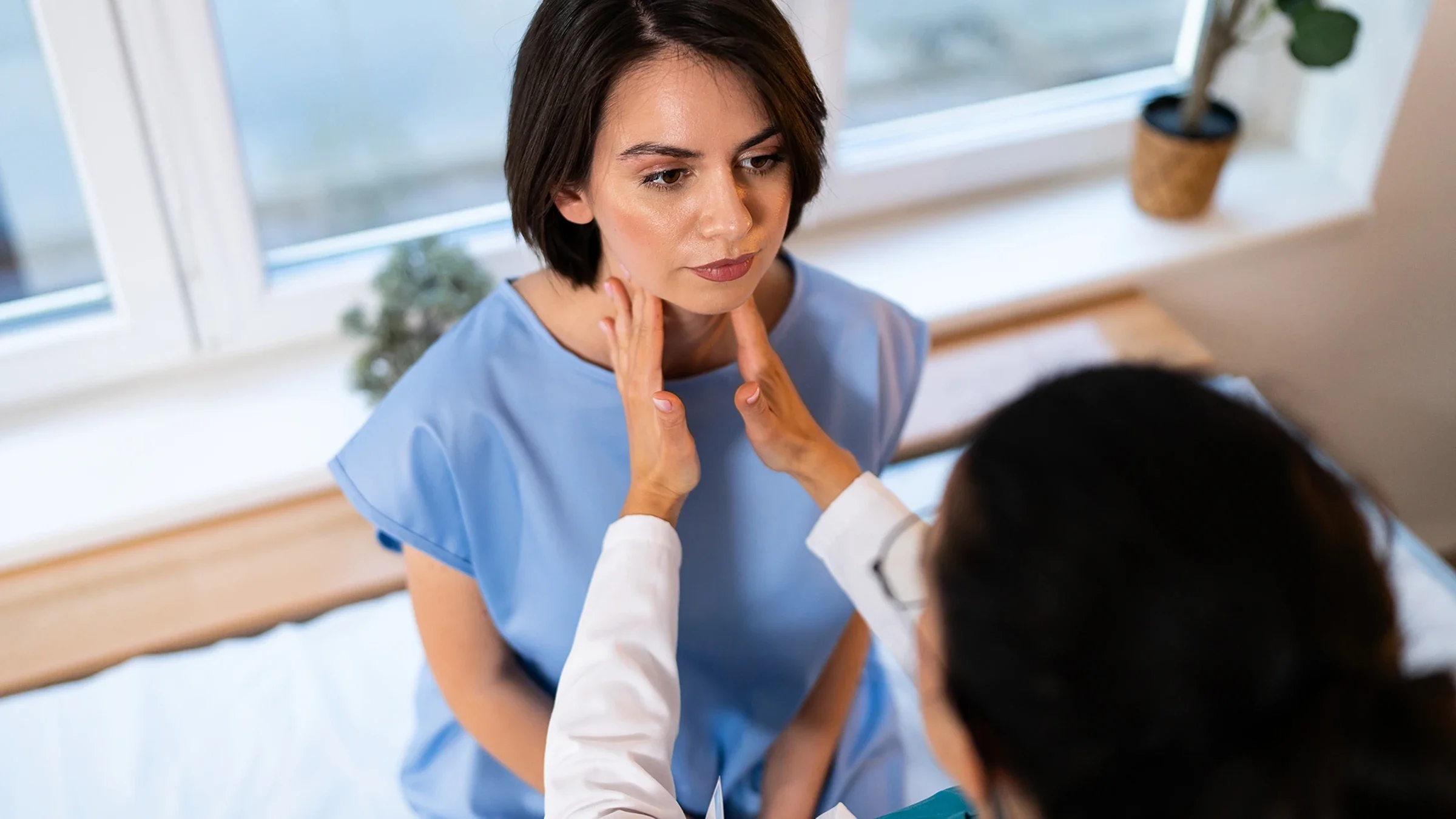 A healthcare professional is examining a patient's thyroid gland.