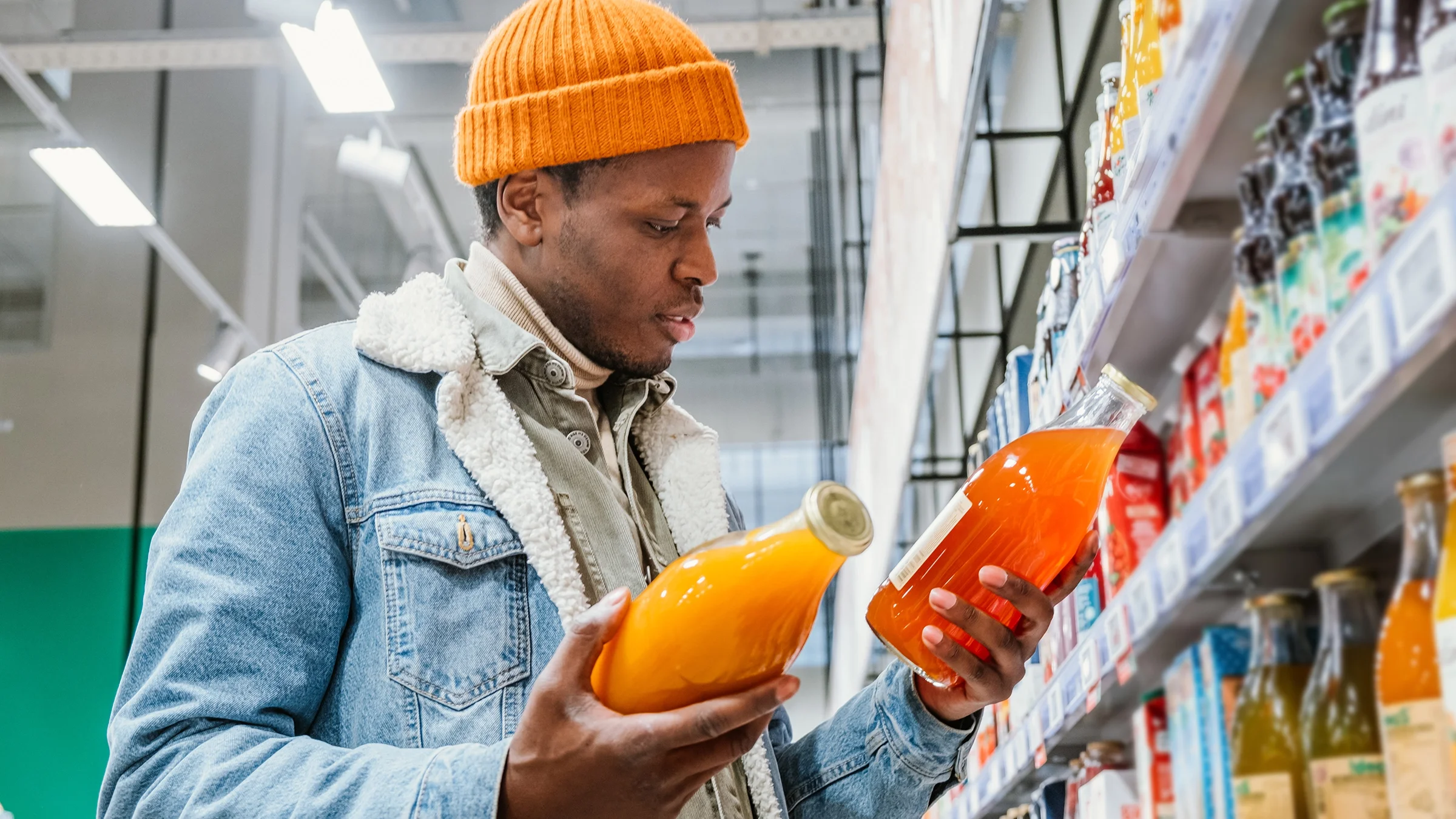 Man examines two juice bottles in a grocery store.
