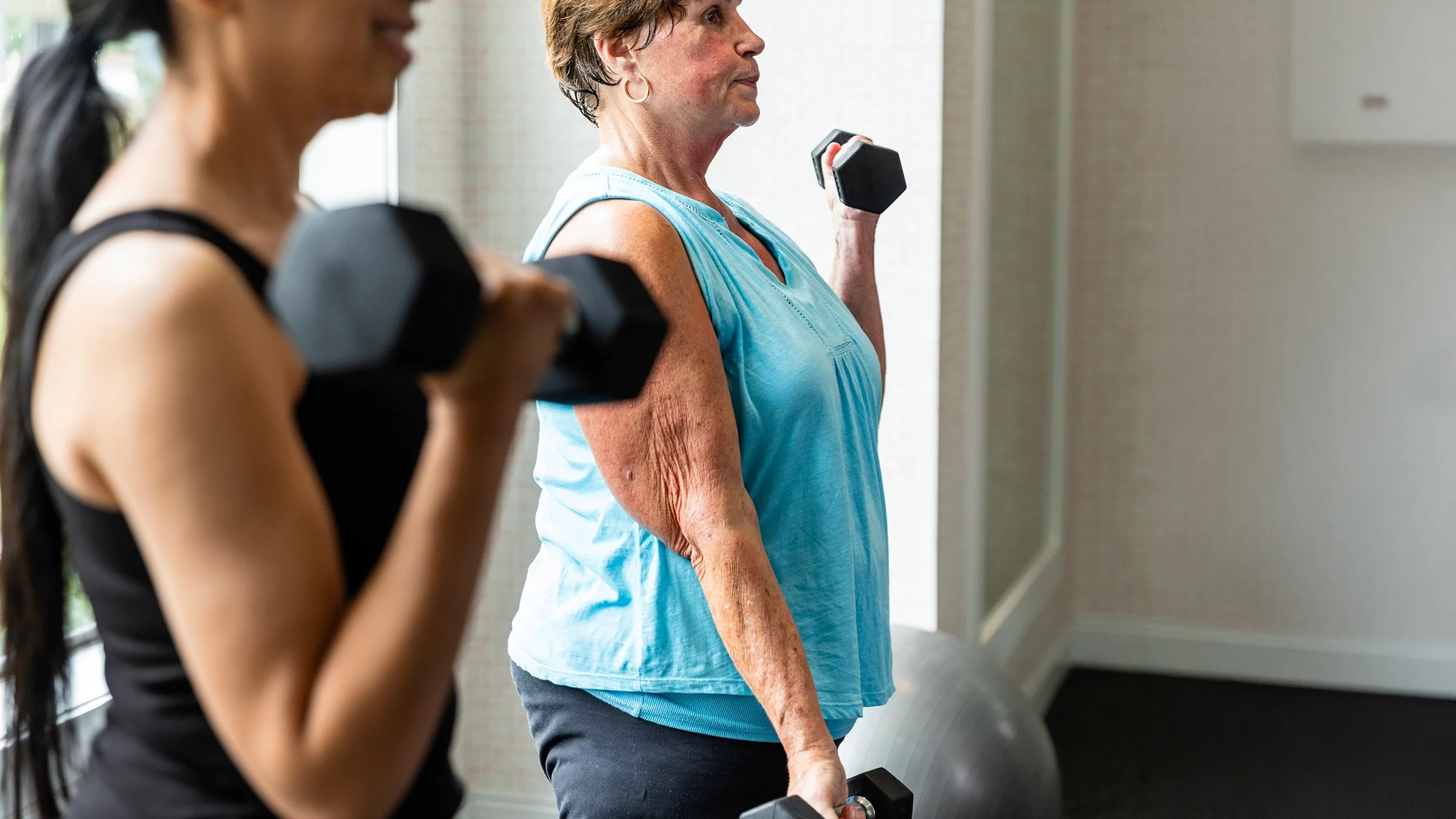 Women working out together in the gym with dumbbells.